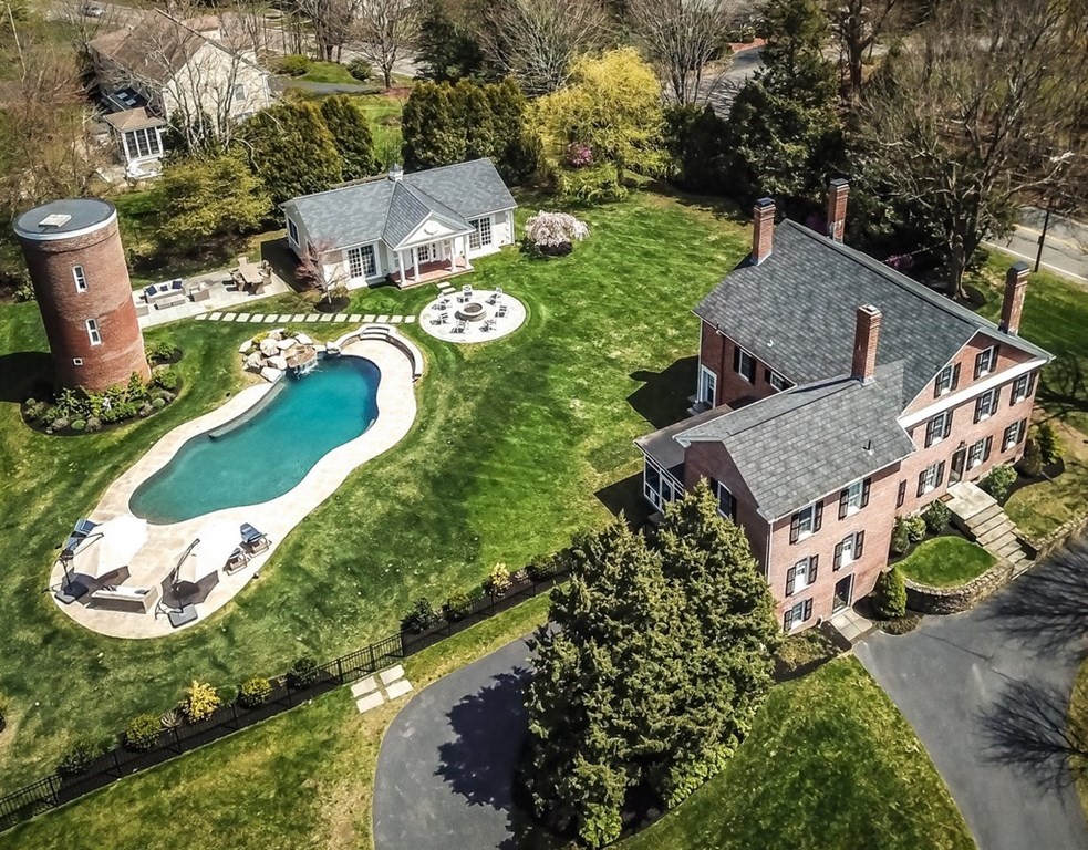 Nestled atop a knoll and embraced by plush lawns and manicured gardens, this stately all brick colonial radiates a charm rarely found in modern architecture. Augmenting its stateliness, four tall chimneys allow for a fireplace in three of the four bedrooms on the second floor as well as the family room and spacious living room on the main floor.  The master suite boasts an oversized shower and a generous walk-in closet with built-ins and an island. Off the updated kitchen, a screened-in porch overlooks the beautifully sculptured pool and waterfall, an additional patio, and a fire pit area—all great for entertaining. To add to the estate’s charm, a brick silo complements the main house and offers storage space just off the pool area.  And still there is more.  A separate guest house accommodates two large rooms with incredible moldings, a U-line refrigerator, a full bath with steam shower, and an oasis with an outside shower.  Converted into a studio, the stone garage can be reinstated.